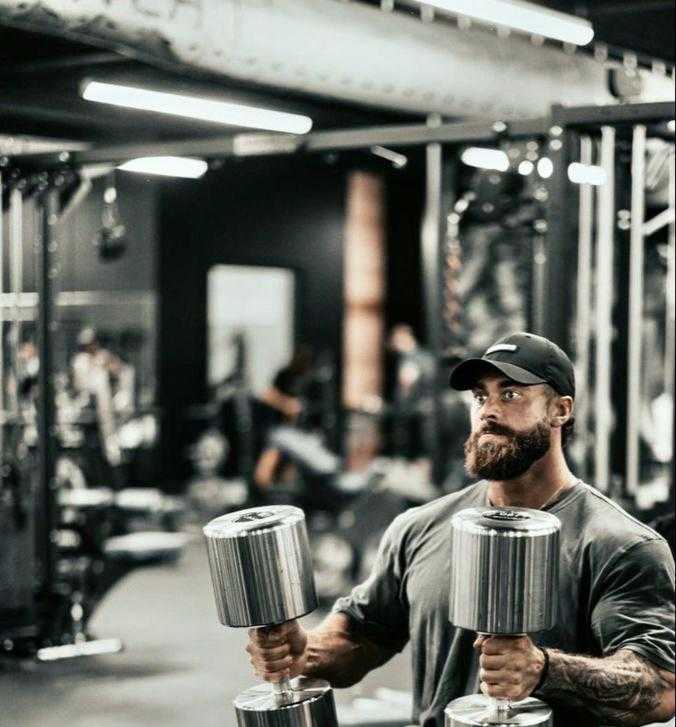 man holding two dumbs in a gym