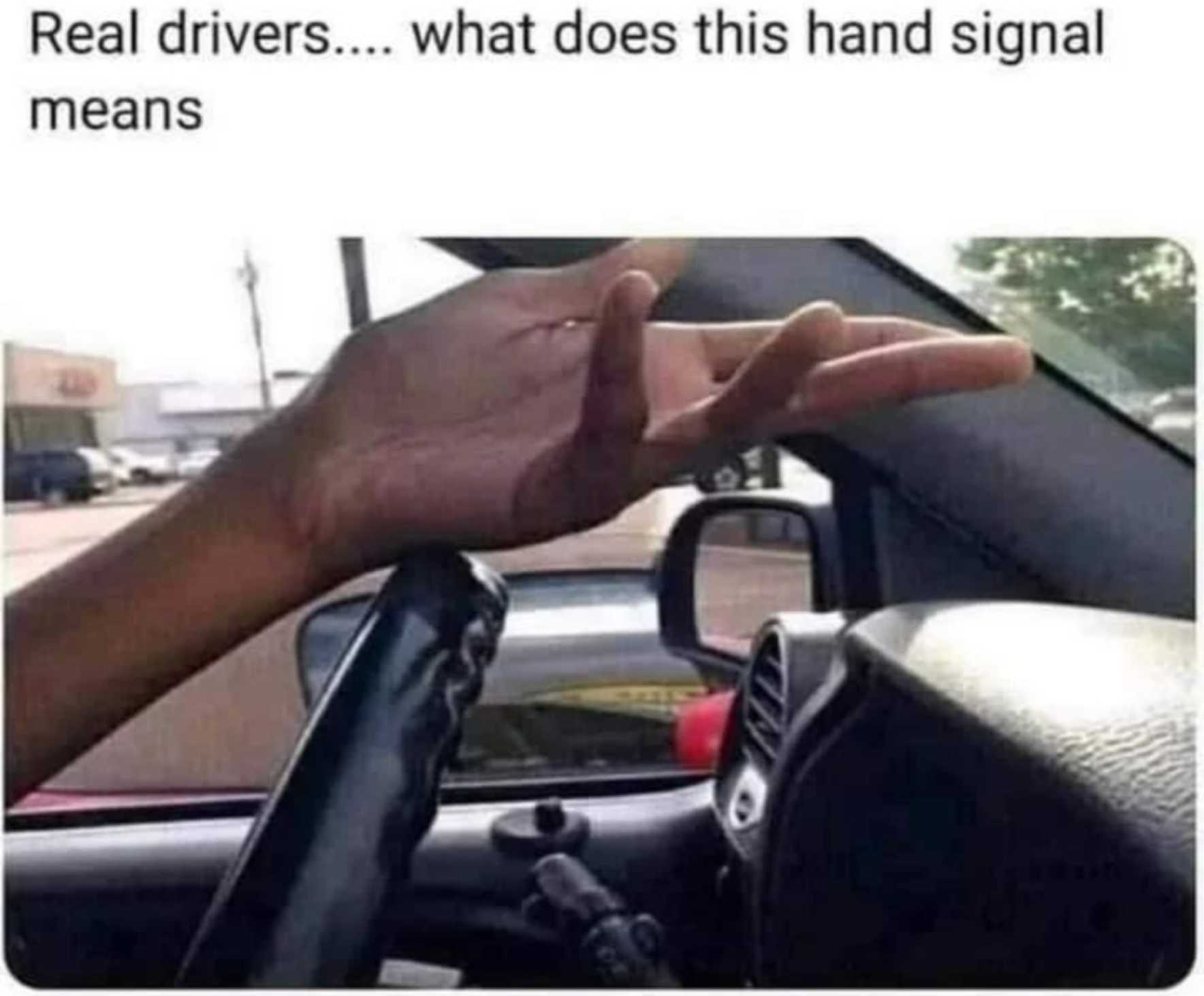 a close up of a person driving a car with a hand on the steering wheel