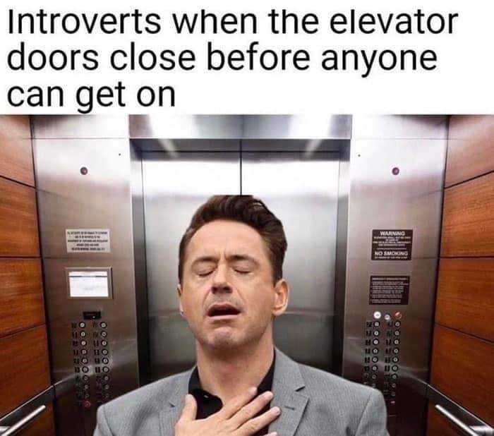 man in a suit standing in an elevator with his hands on his chest