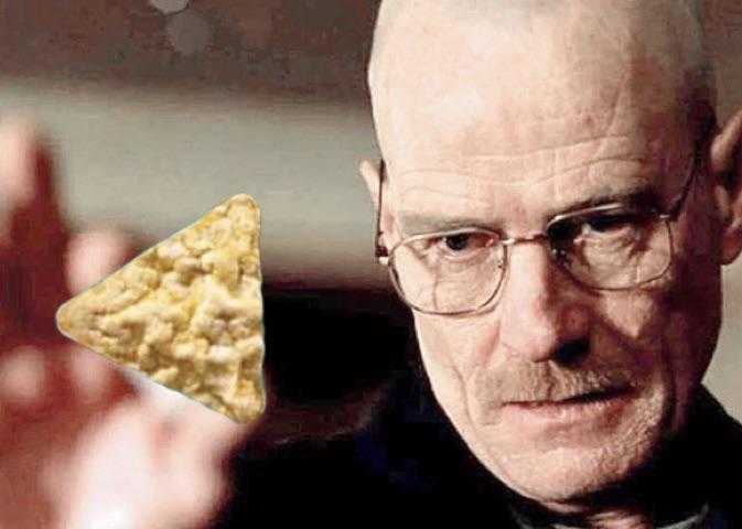 man with glasses holding a piece of corn chips