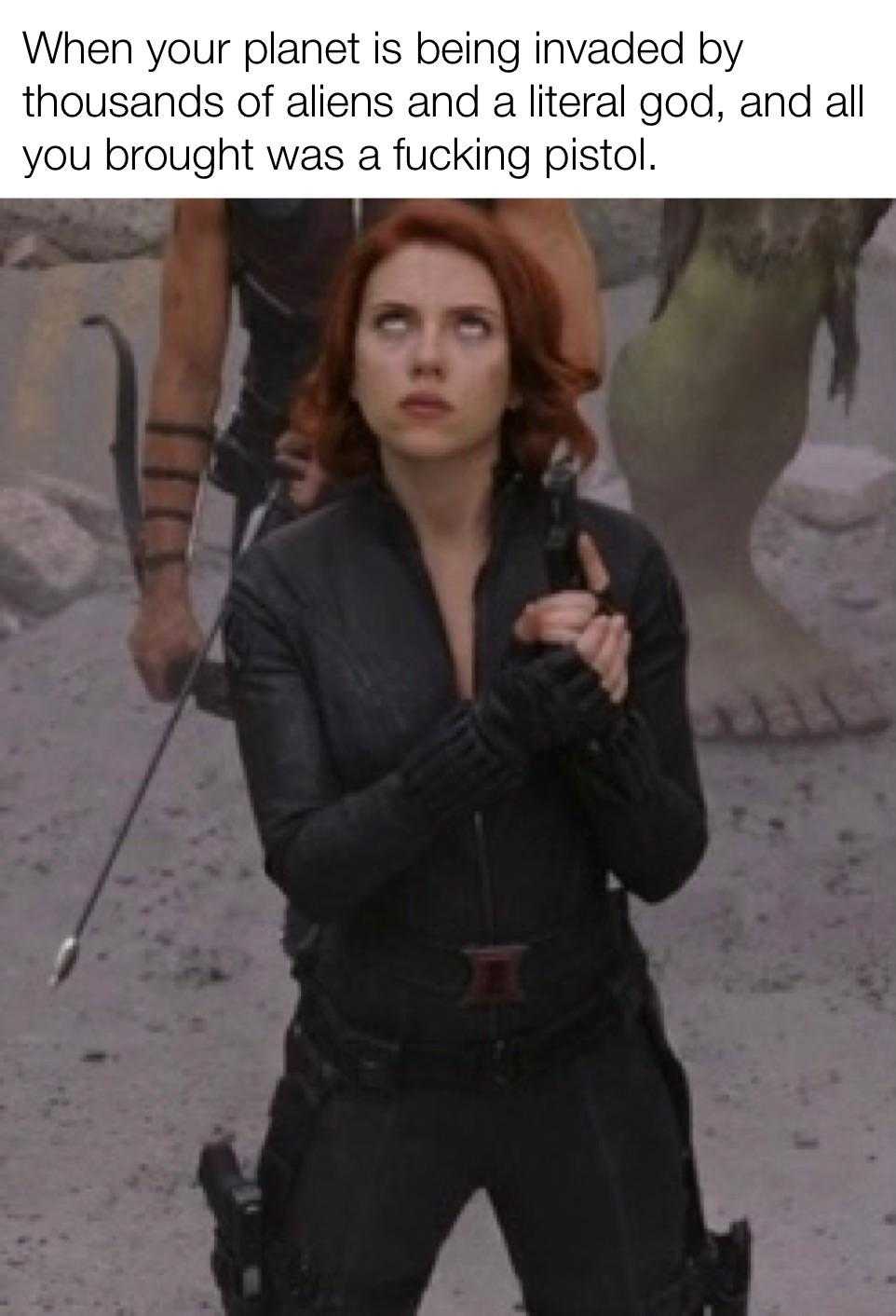 a woman in a black suit holding a sword and standing in front of a group of people