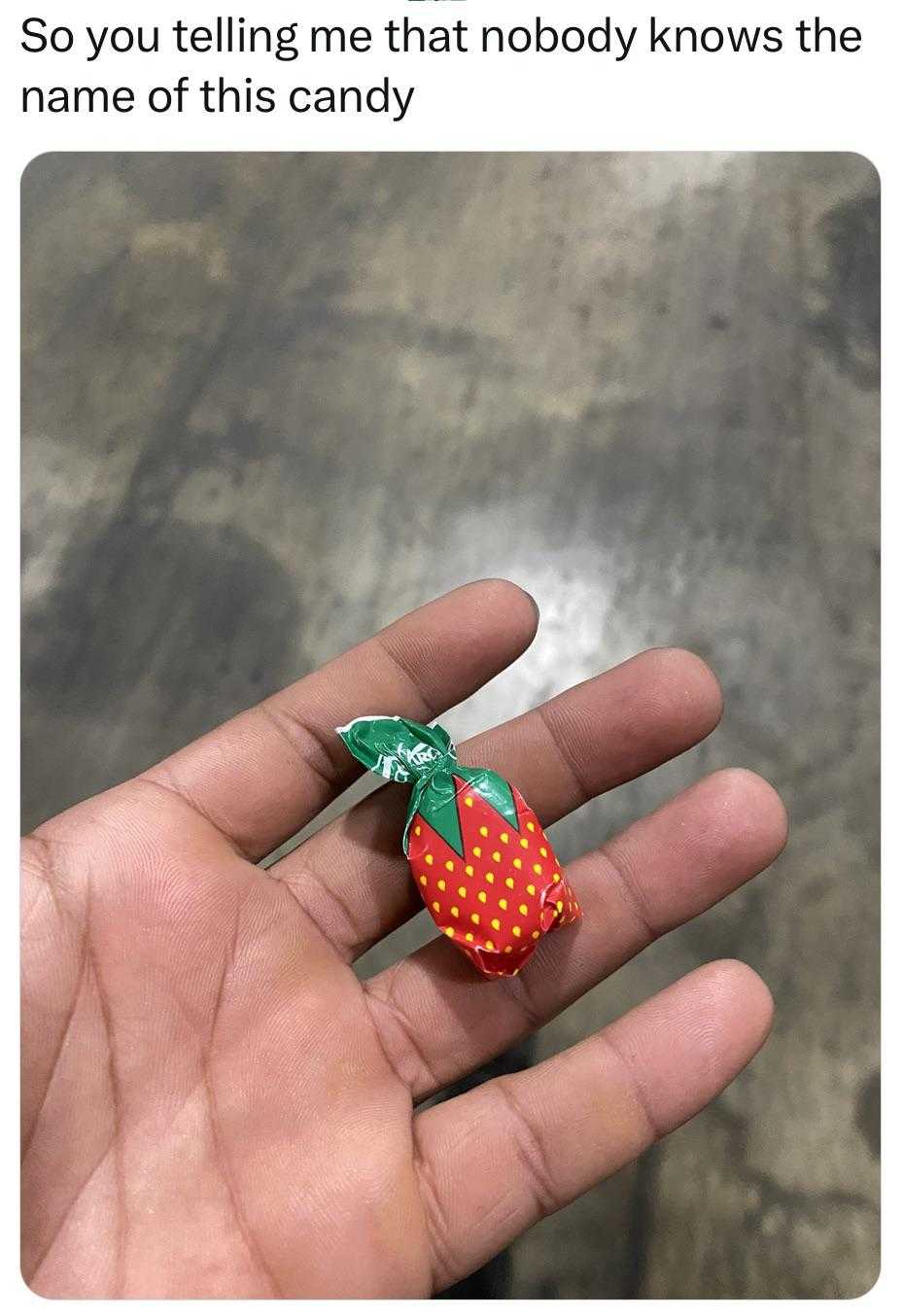 someone holding a small strawberry in their hand with a green leaf on it