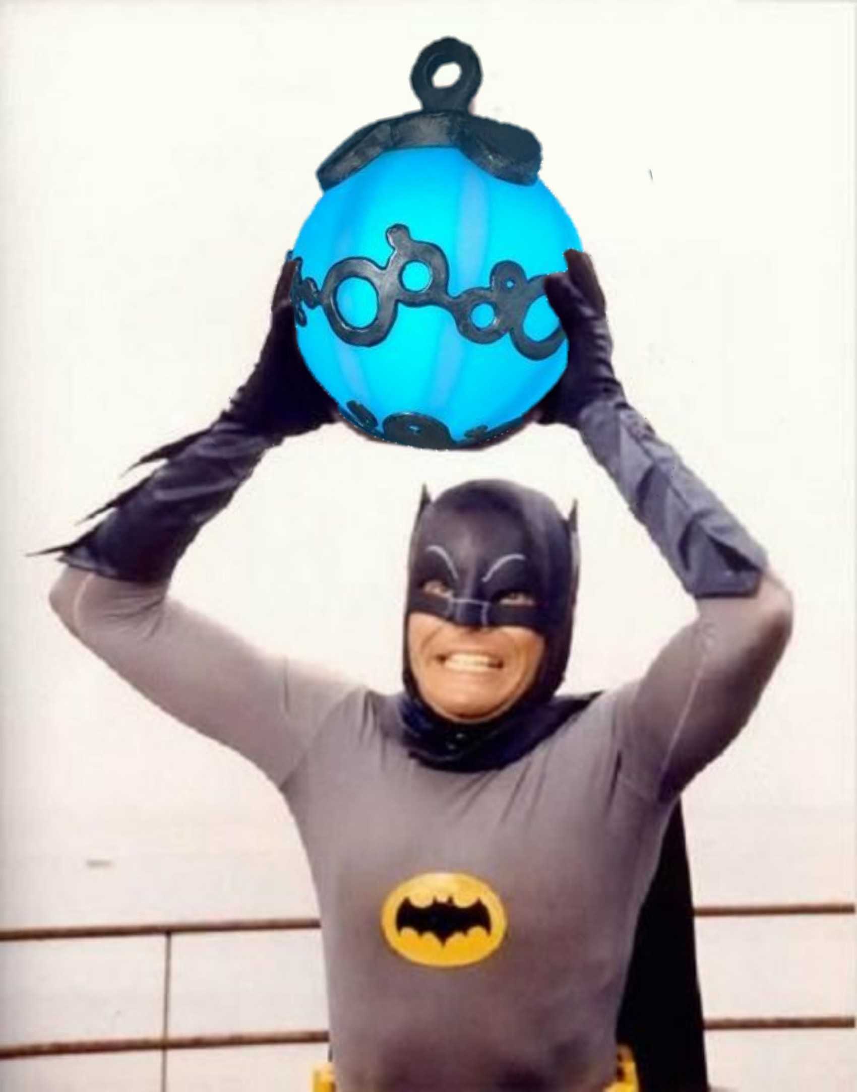 batman holding up a blue balloon with a smiley face on it