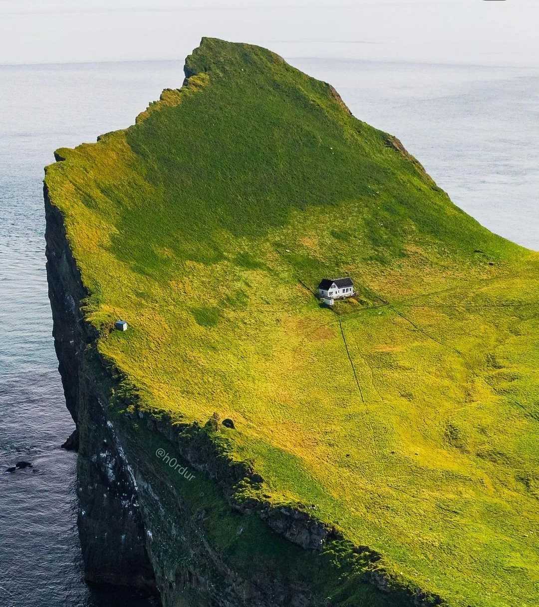 boat on a green island with a small house on the top