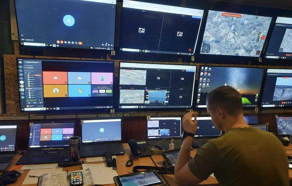 man sitting at a desk with multiple monitors and laptops