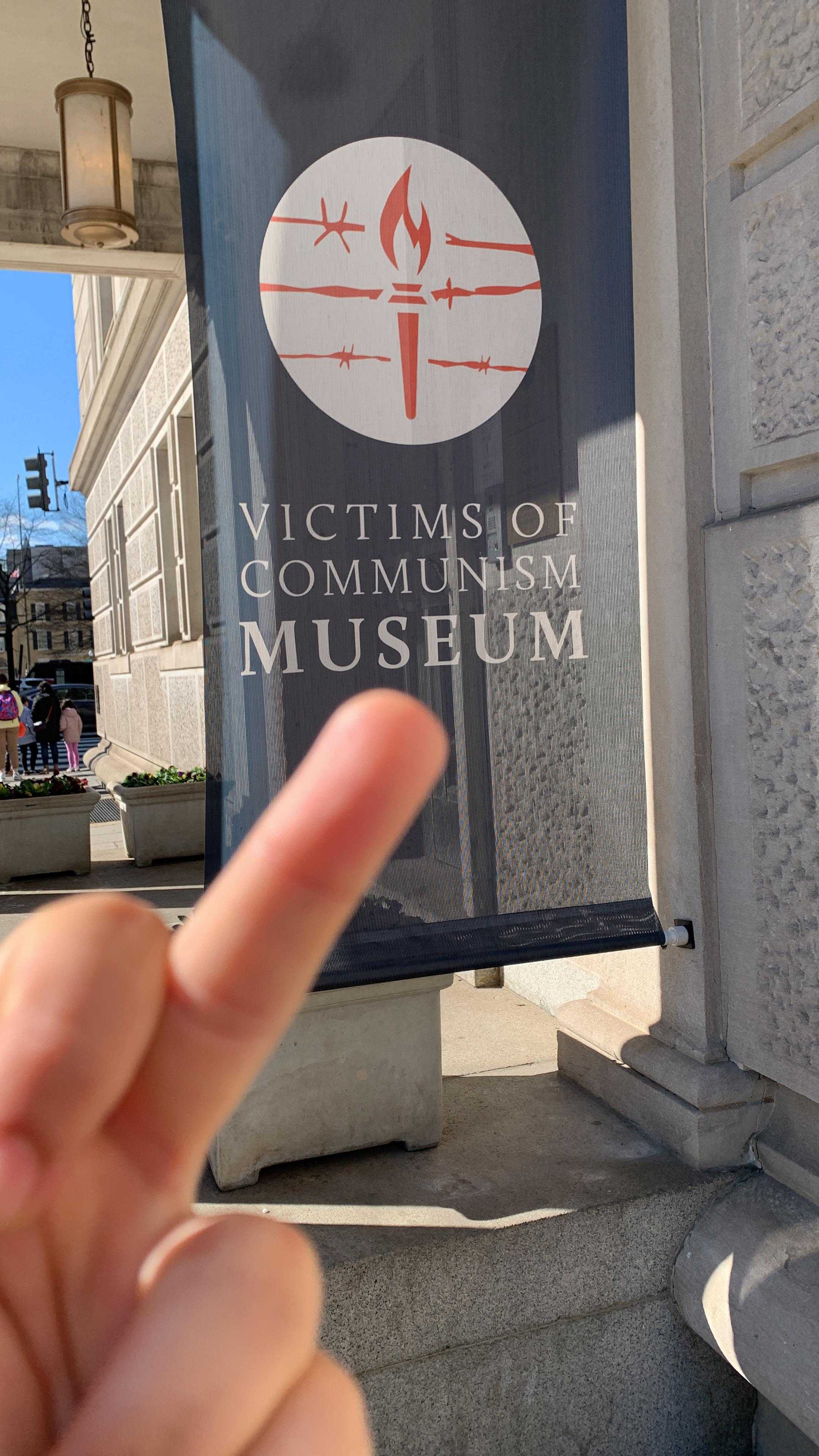 someone is pointing their finger at the sign outside of a museum