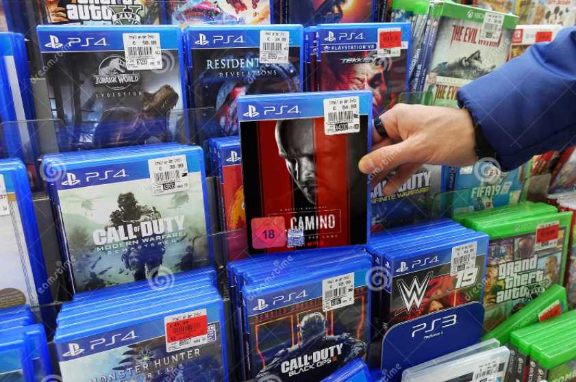 a close up of a person holding a video game in front of a bunch of other video games