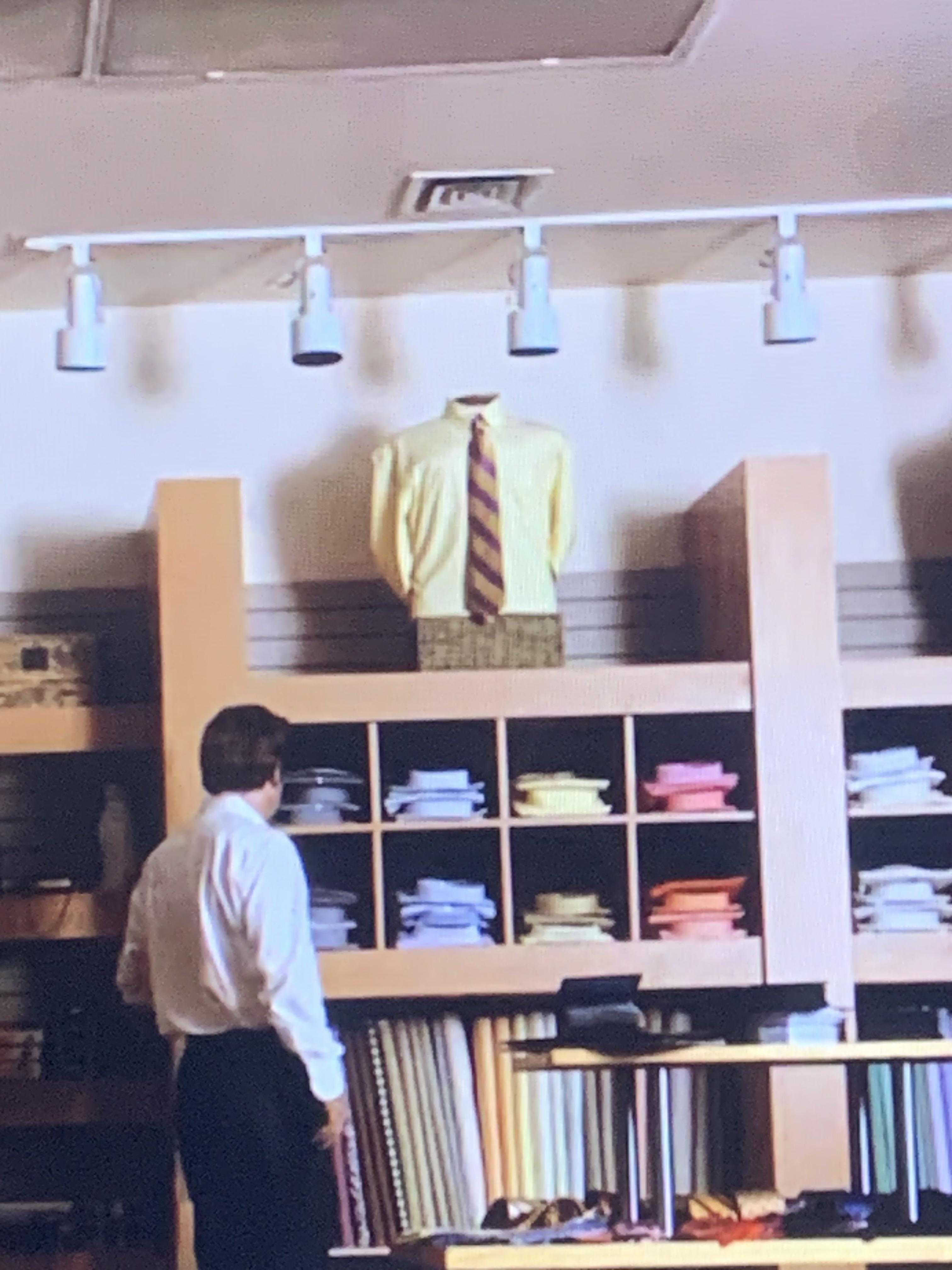 there is a man standing in a room with a shelf of clothes