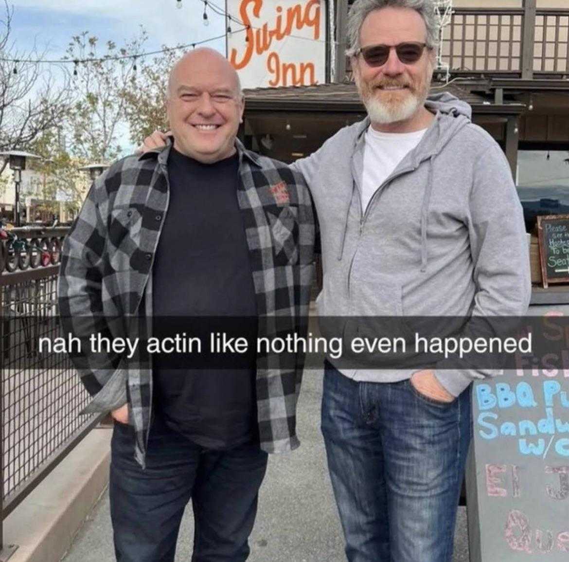 two men standing next to each other in front of a building