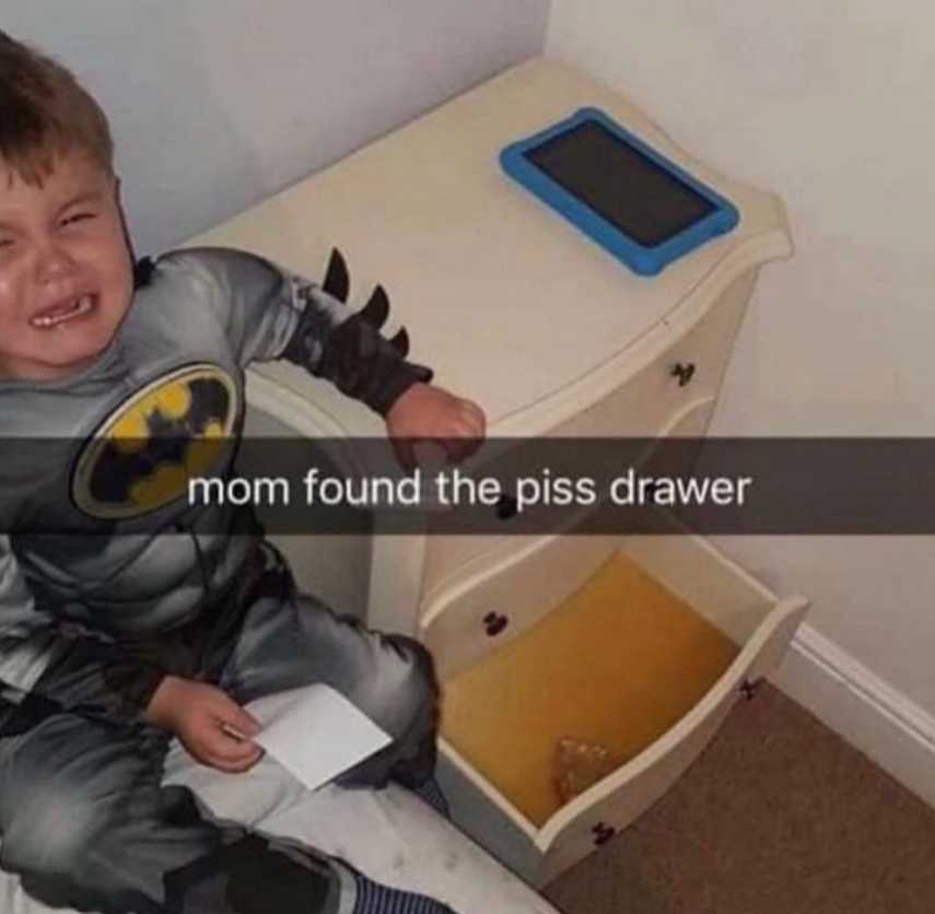 boy sitting on a bed in a batman pajamas with a toy