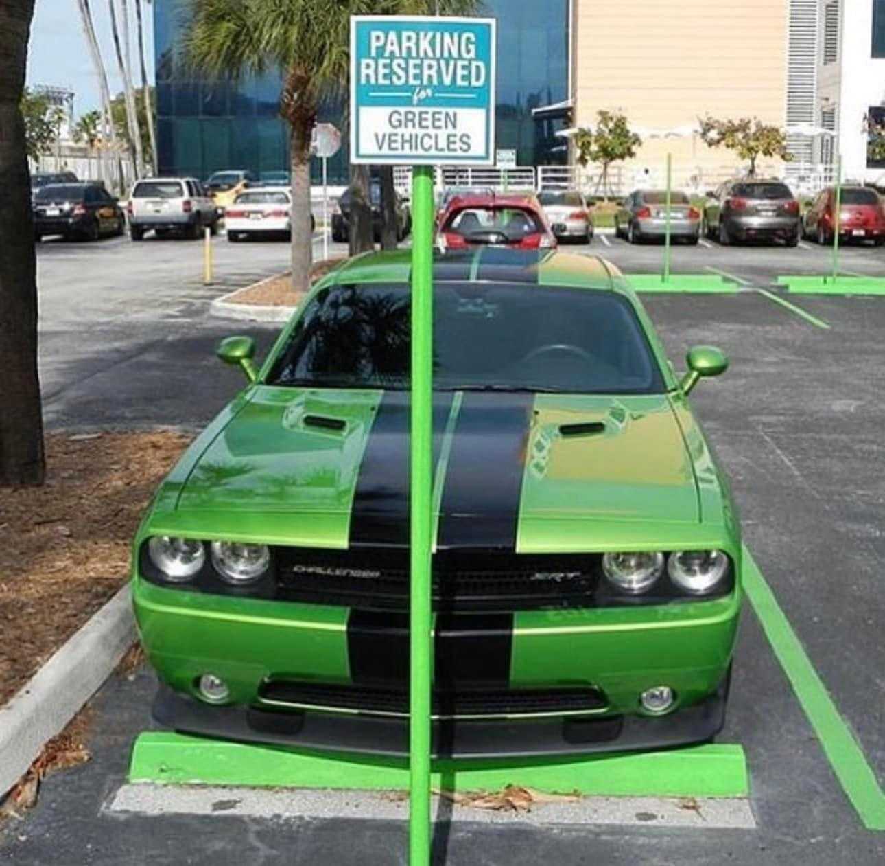 green car parked in a parking lot with a parking reserved sign