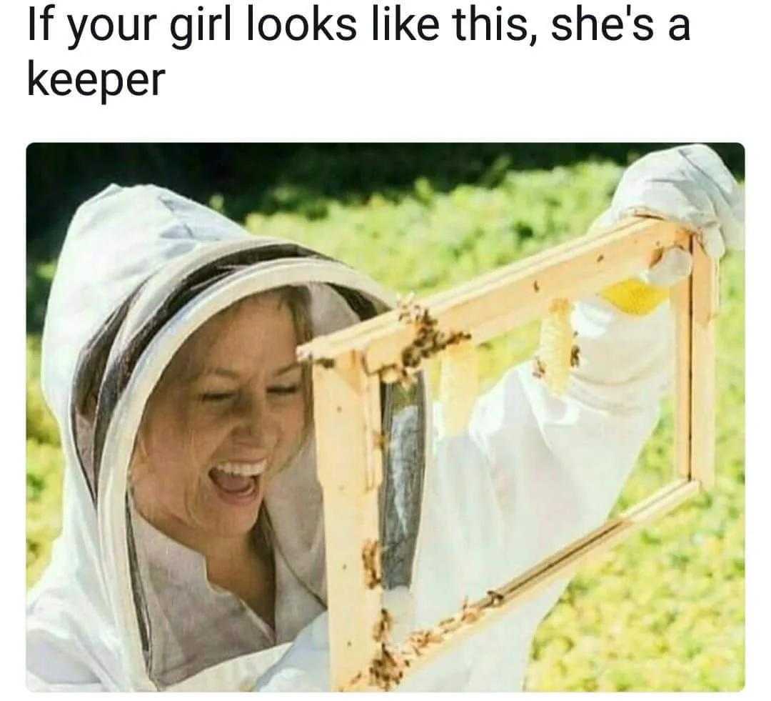 woman in bee suit holding up a frame with bees