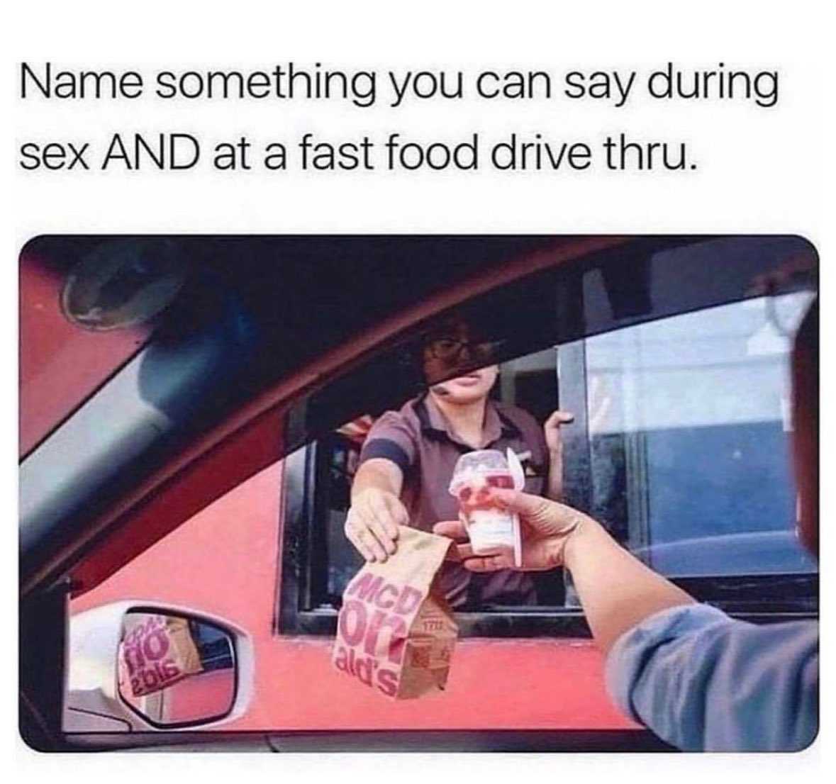 a woman handing a bag of food to a man in a car