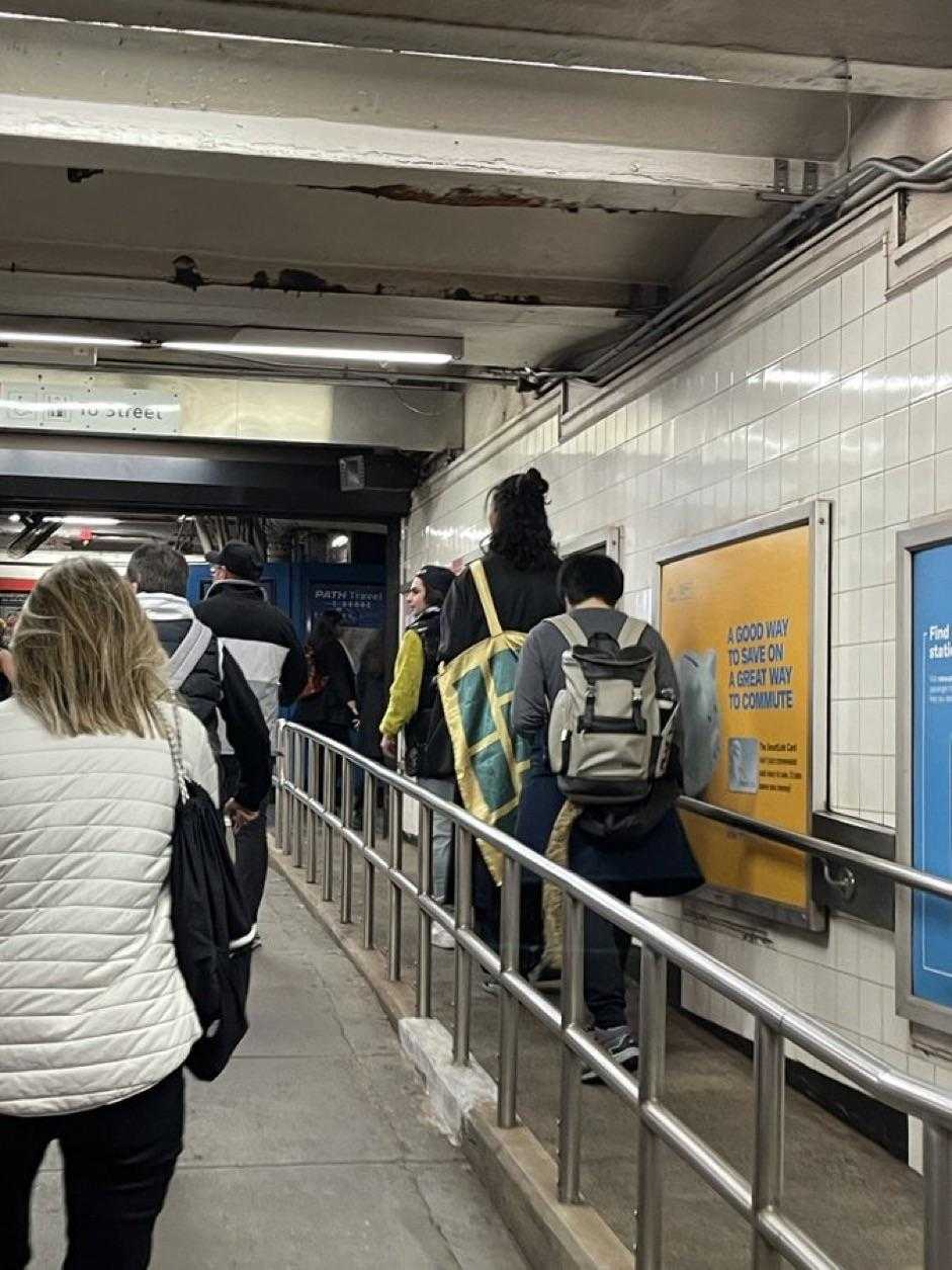 people are walking down a long walkway in a subway station