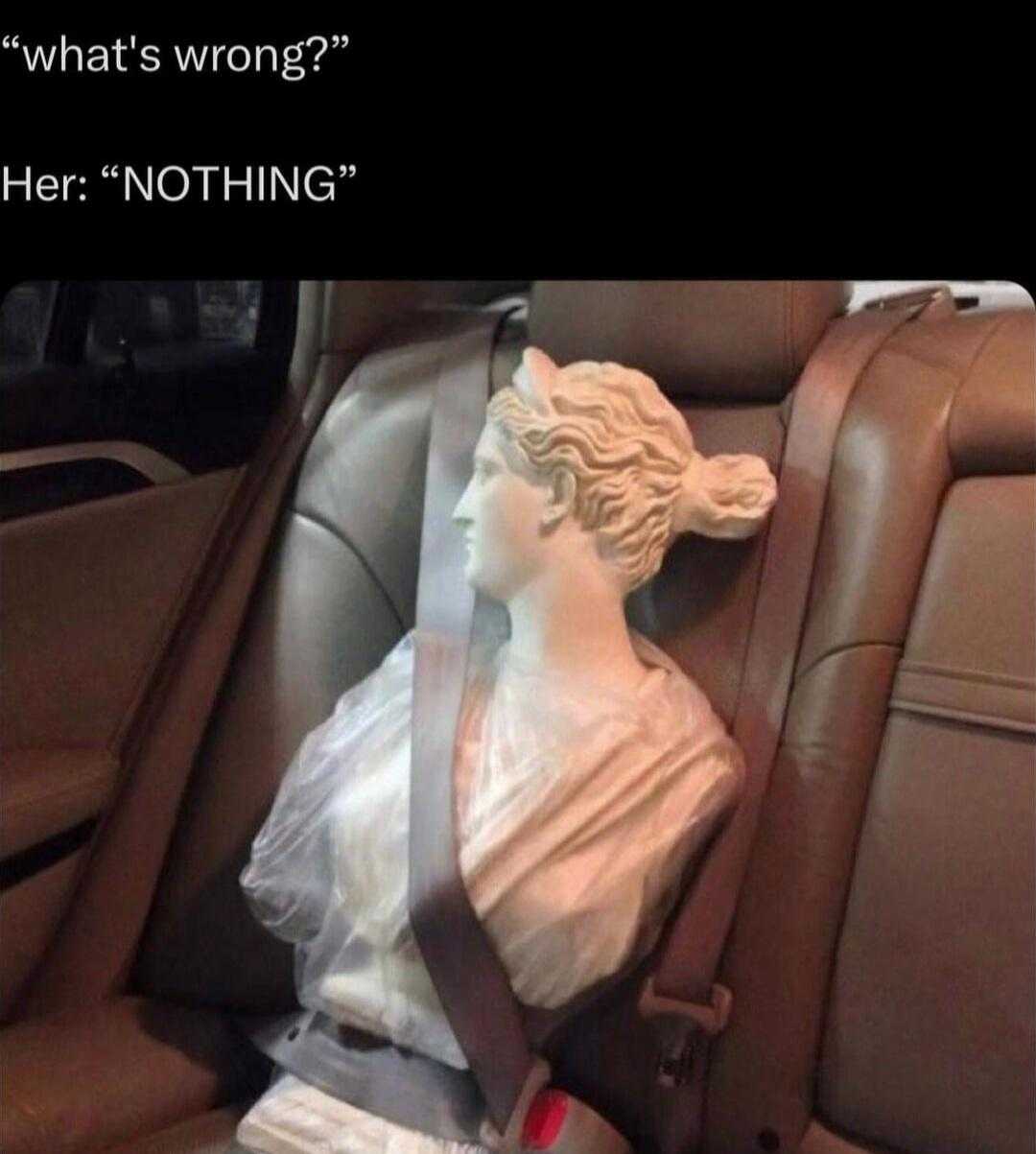 statue of a woman sitting in a car seat with a seat belt