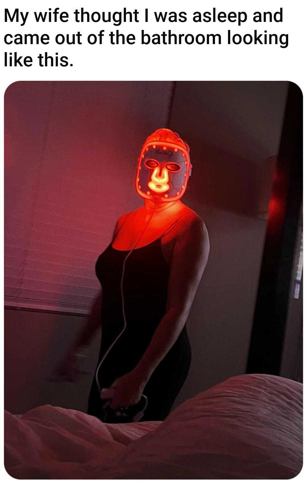 woman wearing a red light mask in a bedroom