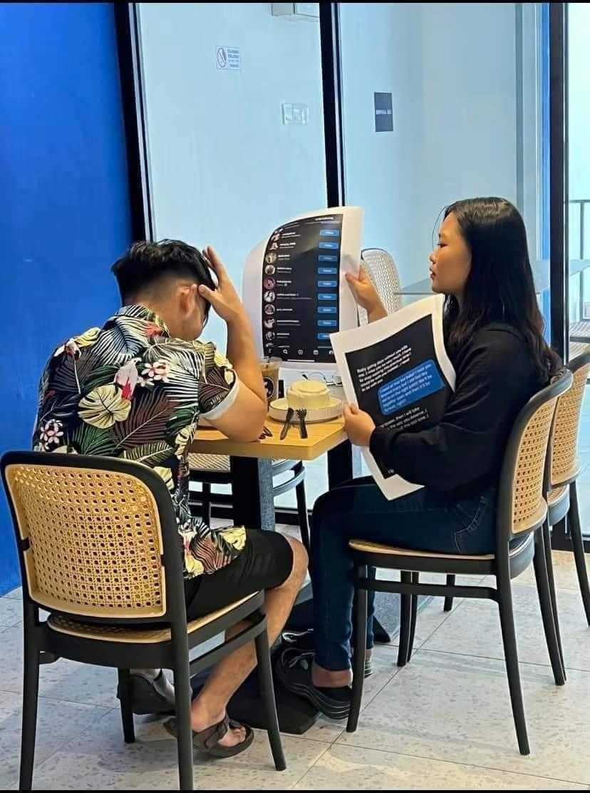 there are two people sitting at a table with a laptop