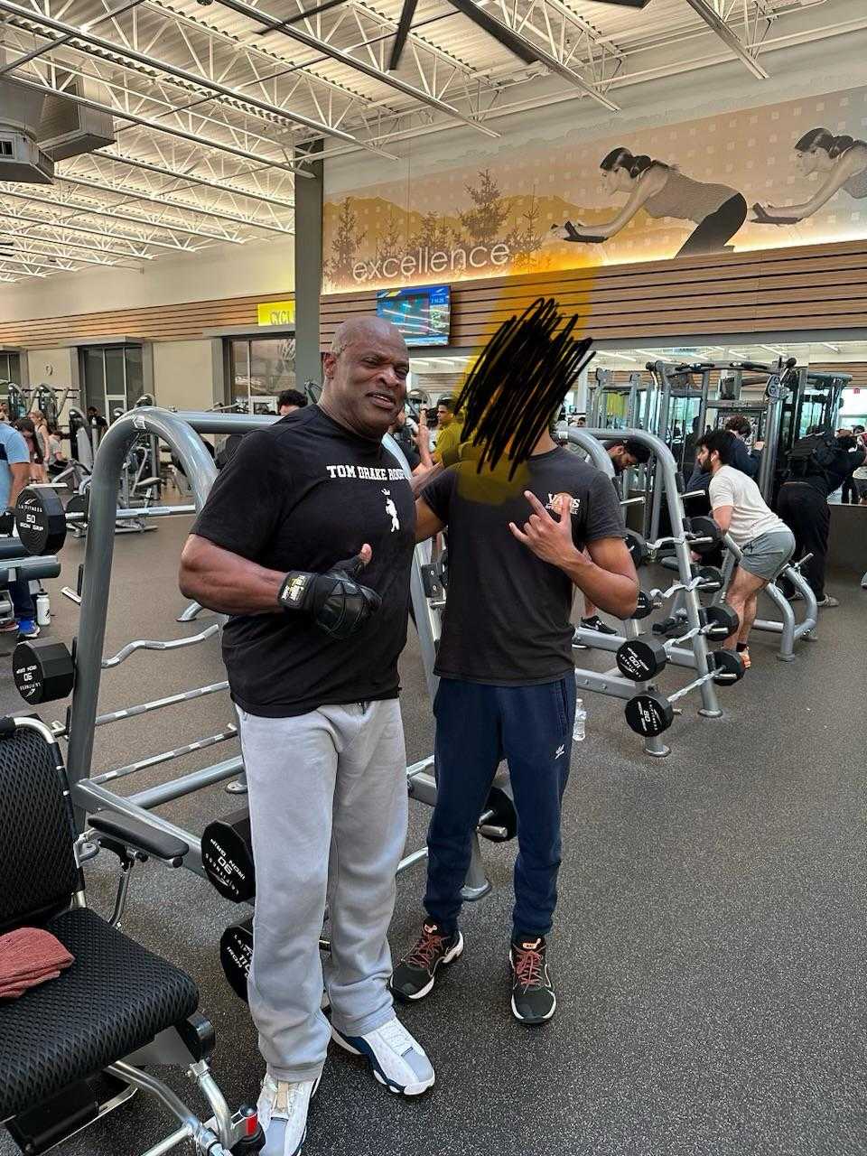 there are two men standing in a gym with a bench