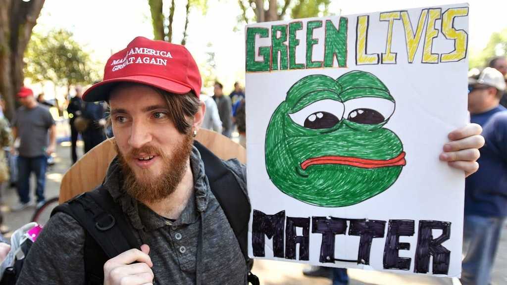 man holding a sign with a drawing of a frog