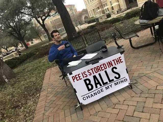 man sitting at a table with a sign that says rest is stored in the balls change my mind