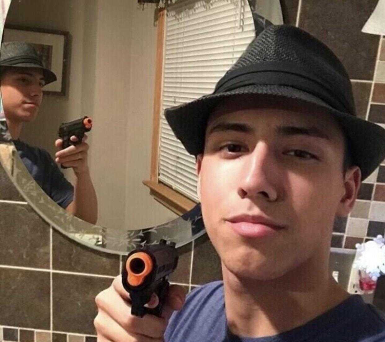 there is a man taking a selfie in the mirror with a gun