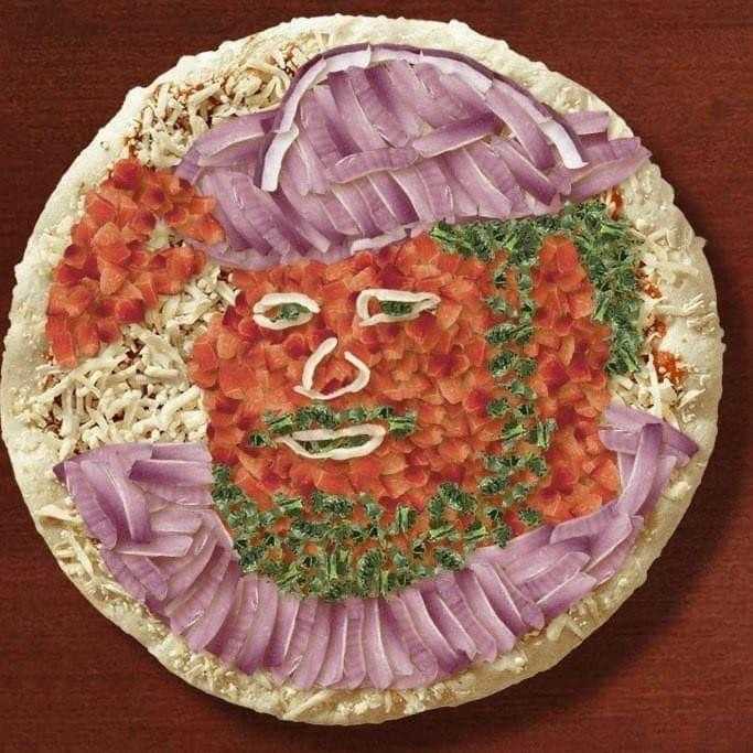 a close up of a pizza with a face made of vegetables