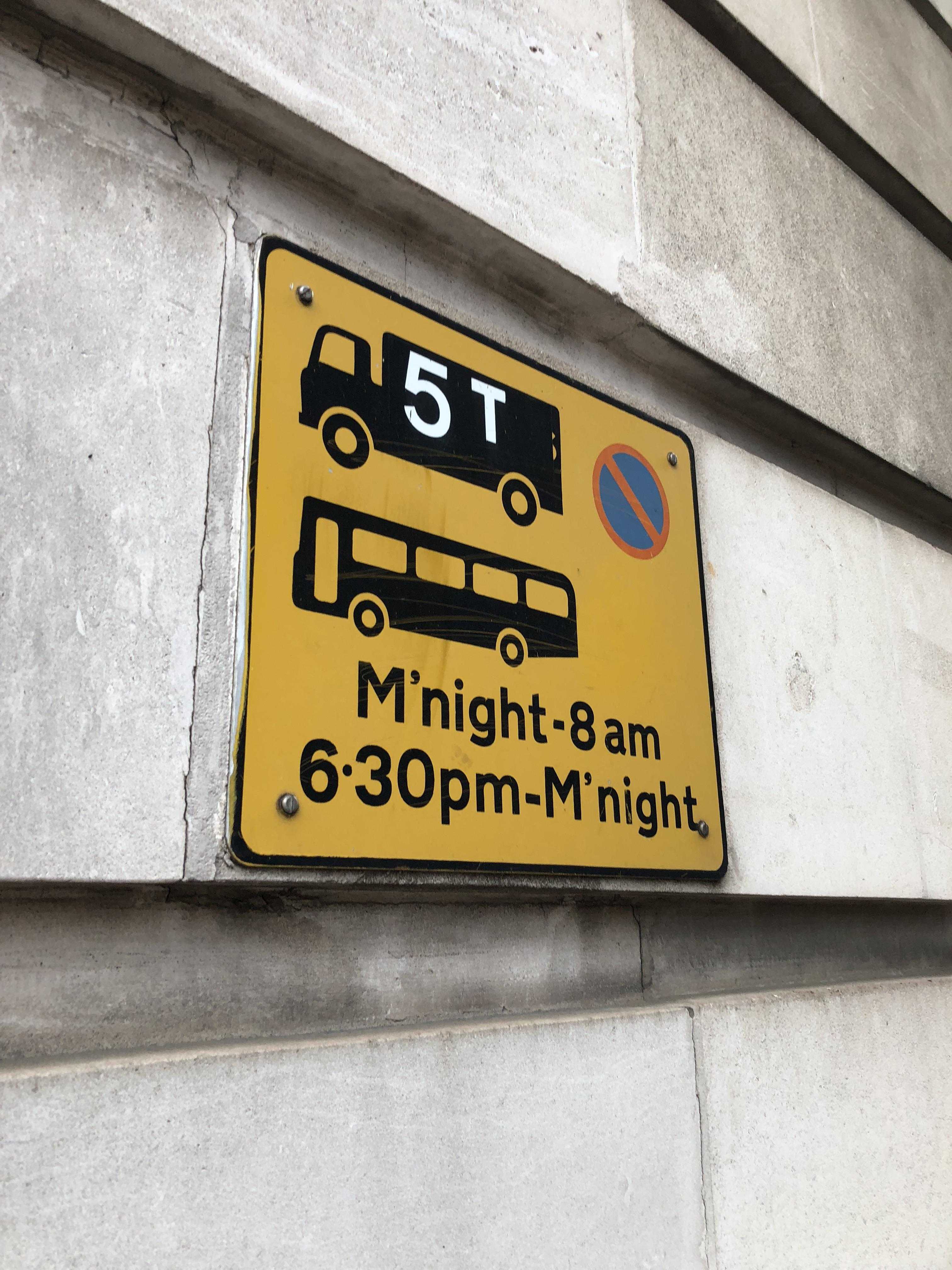 yellow sign on a building indicating the speed limit of a bus