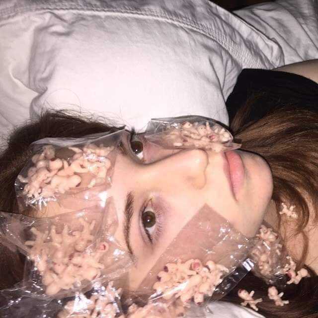 there is a woman laying in bed with a plastic bag on her face