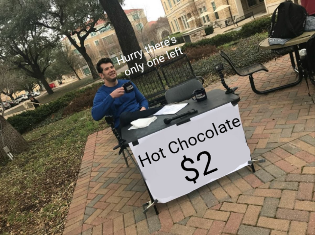 man sitting at a table with a hot chocolate sign