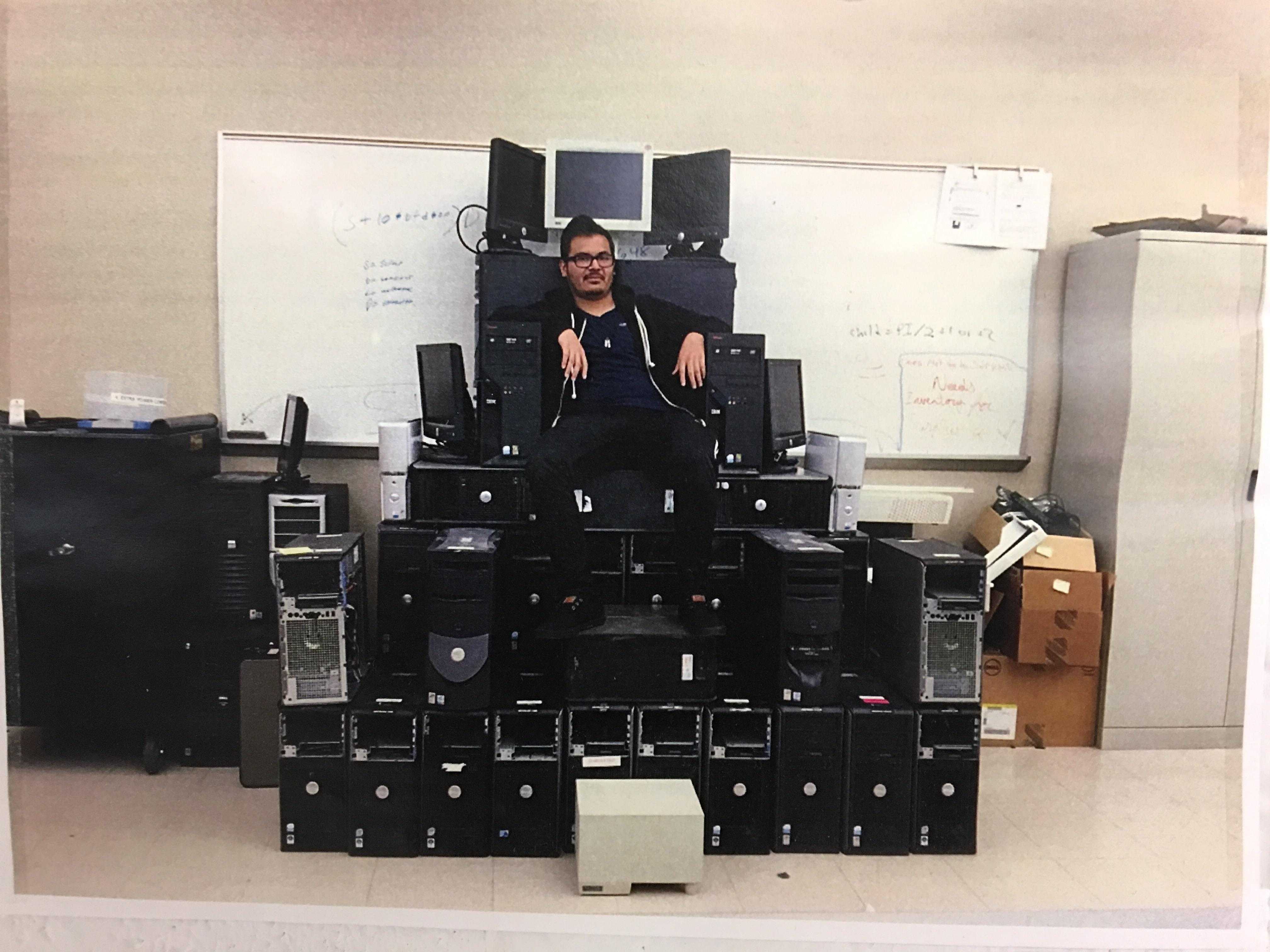 there is a man sitting on a pile of electronics in a room