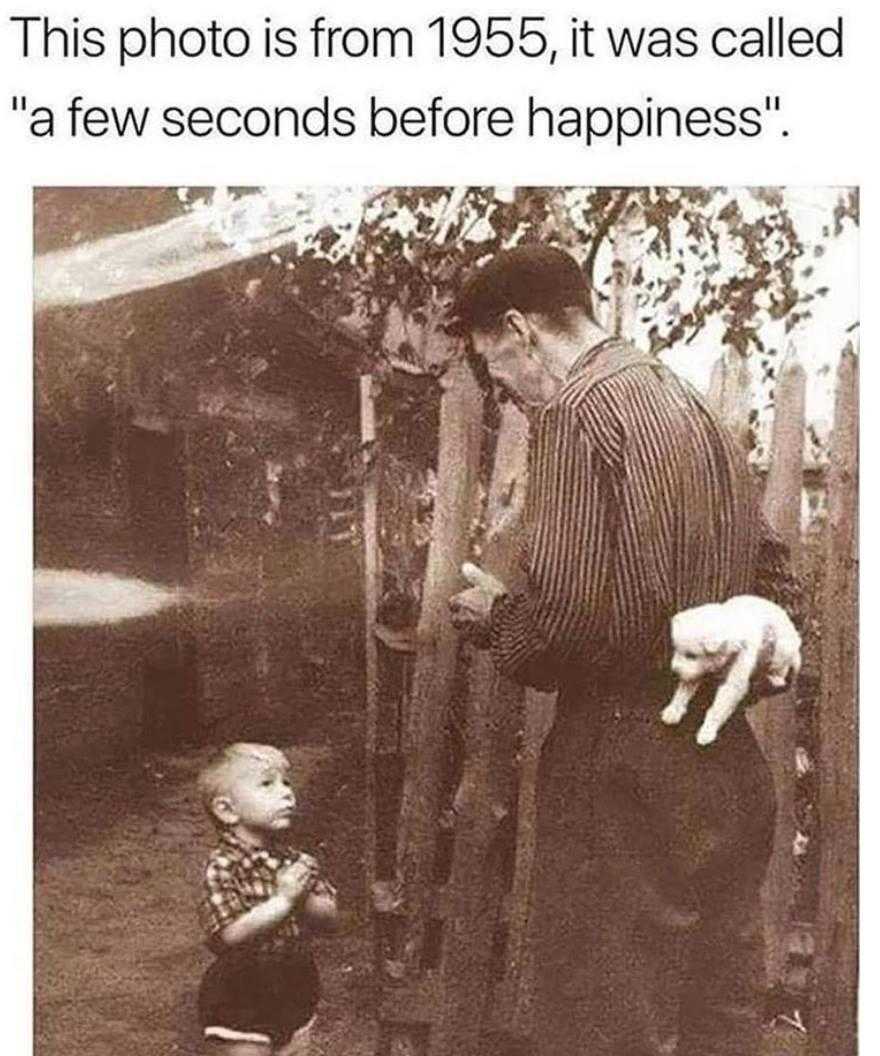 there is a man holding a cat and a baby standing next to a fence