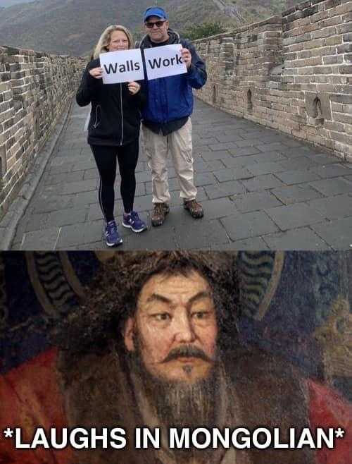 a couple of people standing on a wall holding a sign