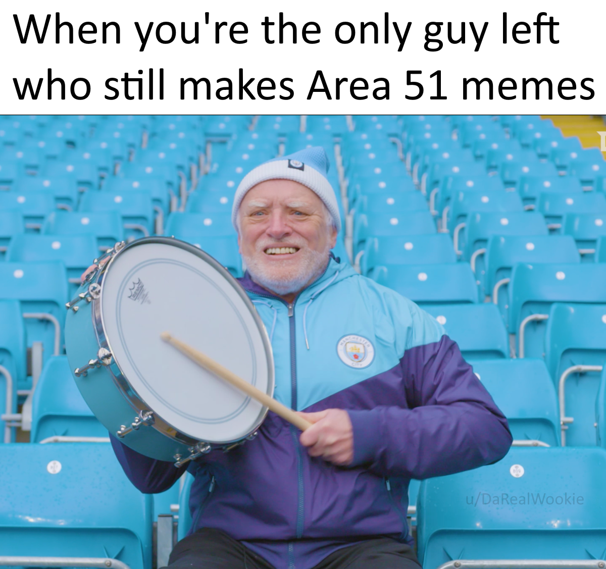 man sitting in a stadium holding a drum and a drum stick