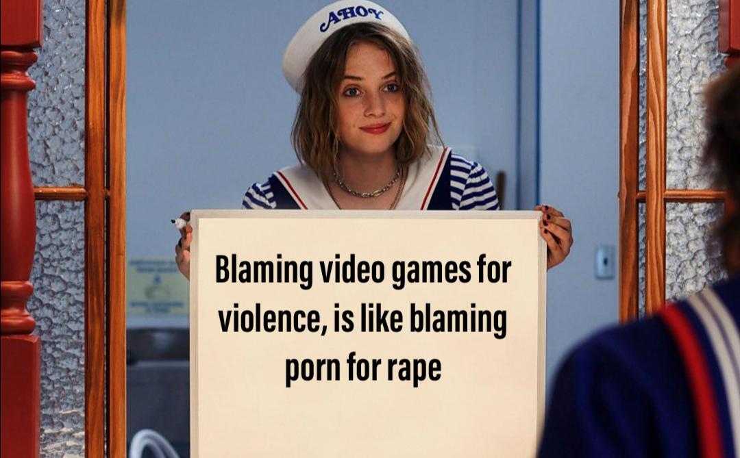 there is a woman holding a sign that says blame video games for violence is like blaming porn for rape