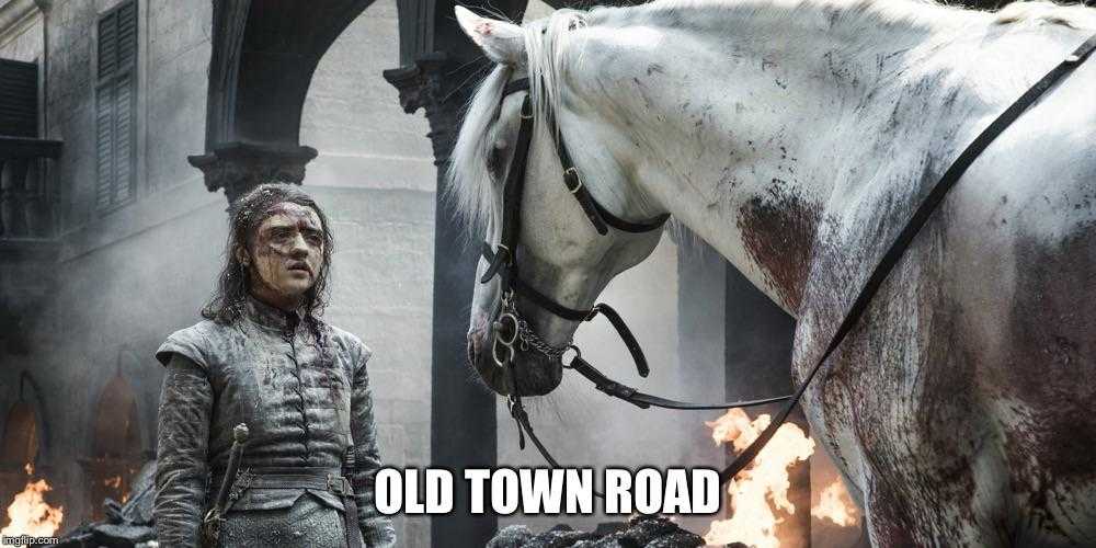 there is a man standing next to a horse in a town