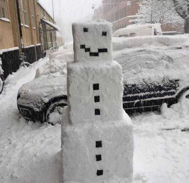 snow covered snowman on the side of the road in the snow