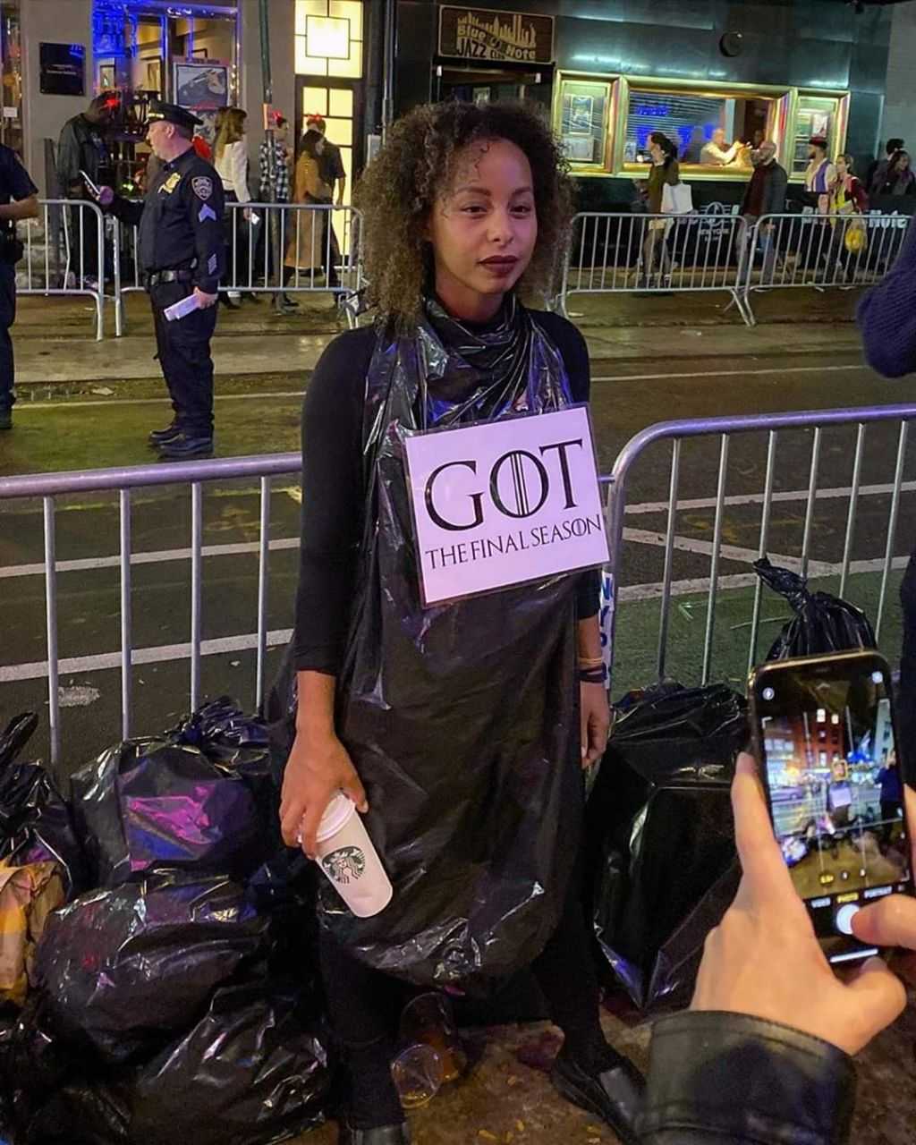 there is a woman standing next to a pile of garbage holding a cell phone