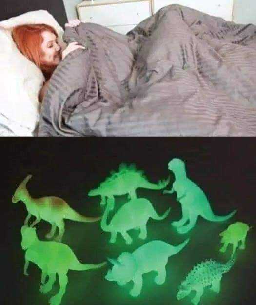 a close up of a person laying in bed with a bunch of dinosaurs