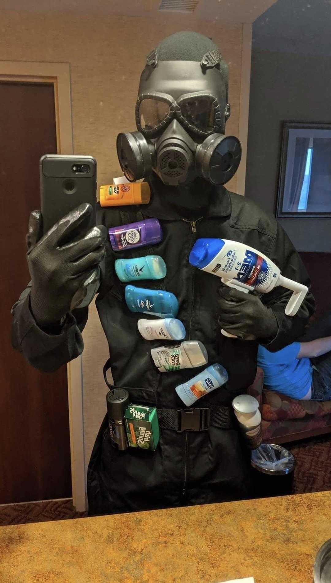 man in gas mask holding up a cell phone and a lot of soap