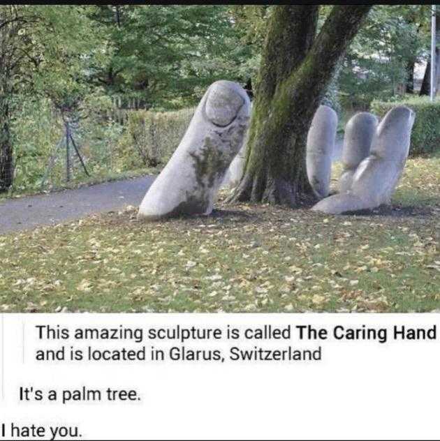 there is a statue of two hands that are sitting next to a tree