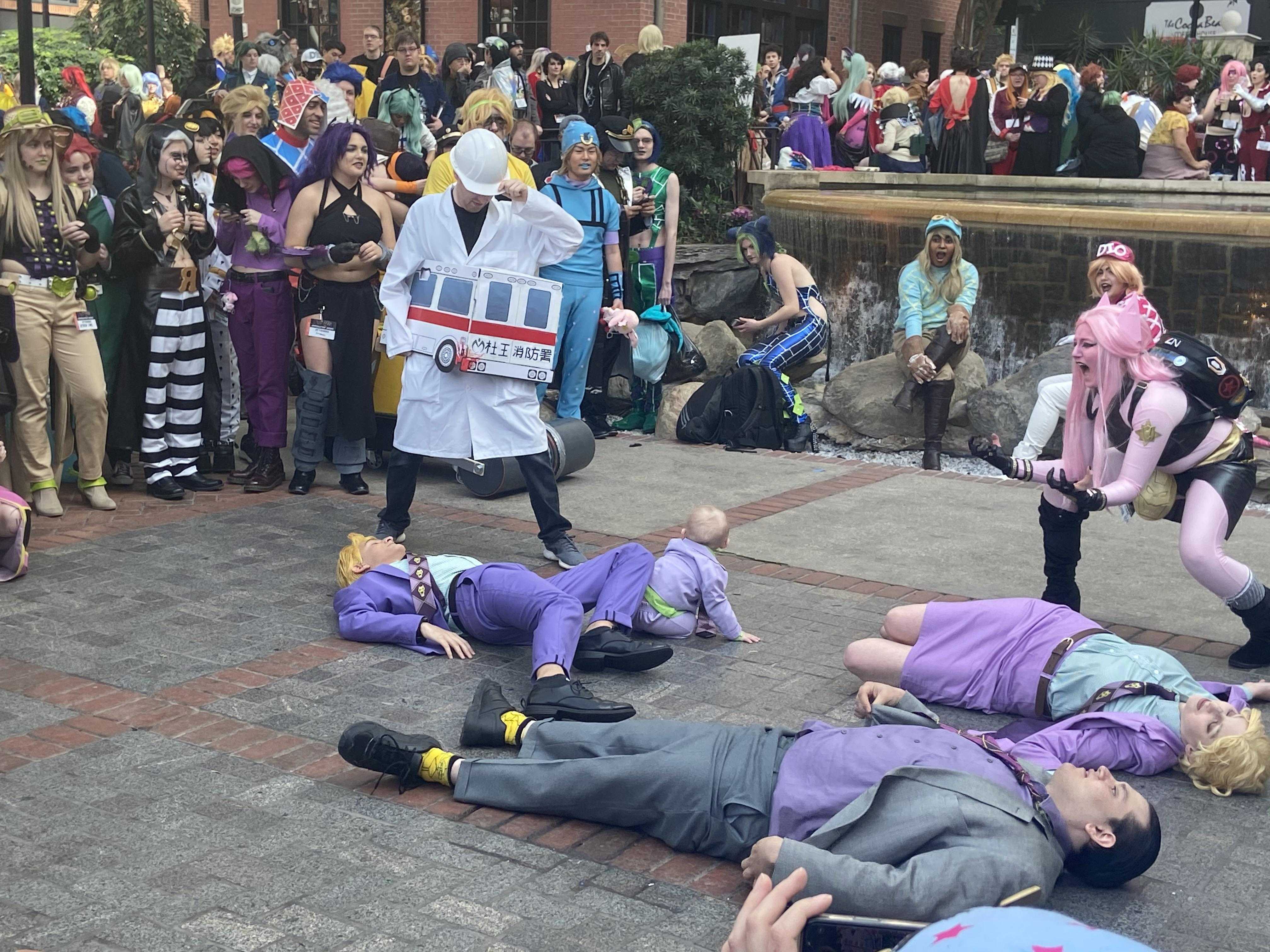 several people in costumes are laying on the ground with a crowd of people