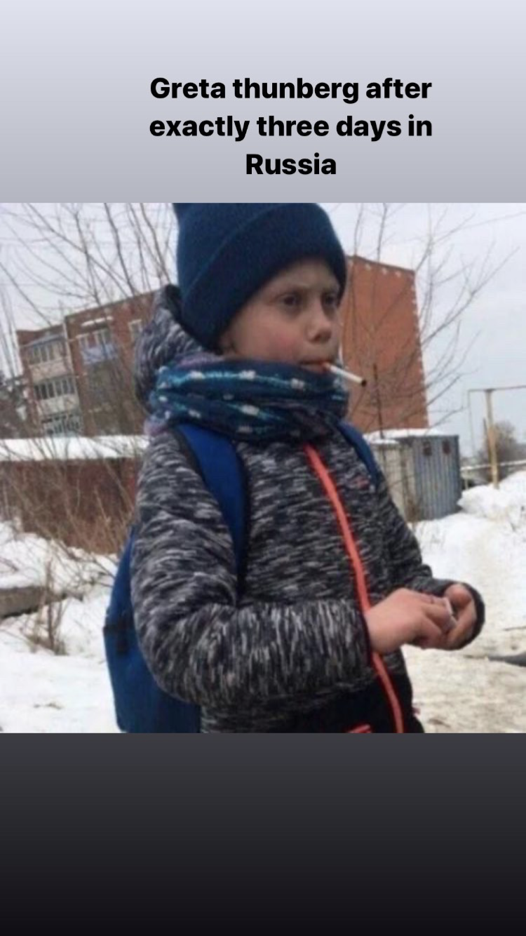 a close up of a child in a jacket and hat holding a cigarette