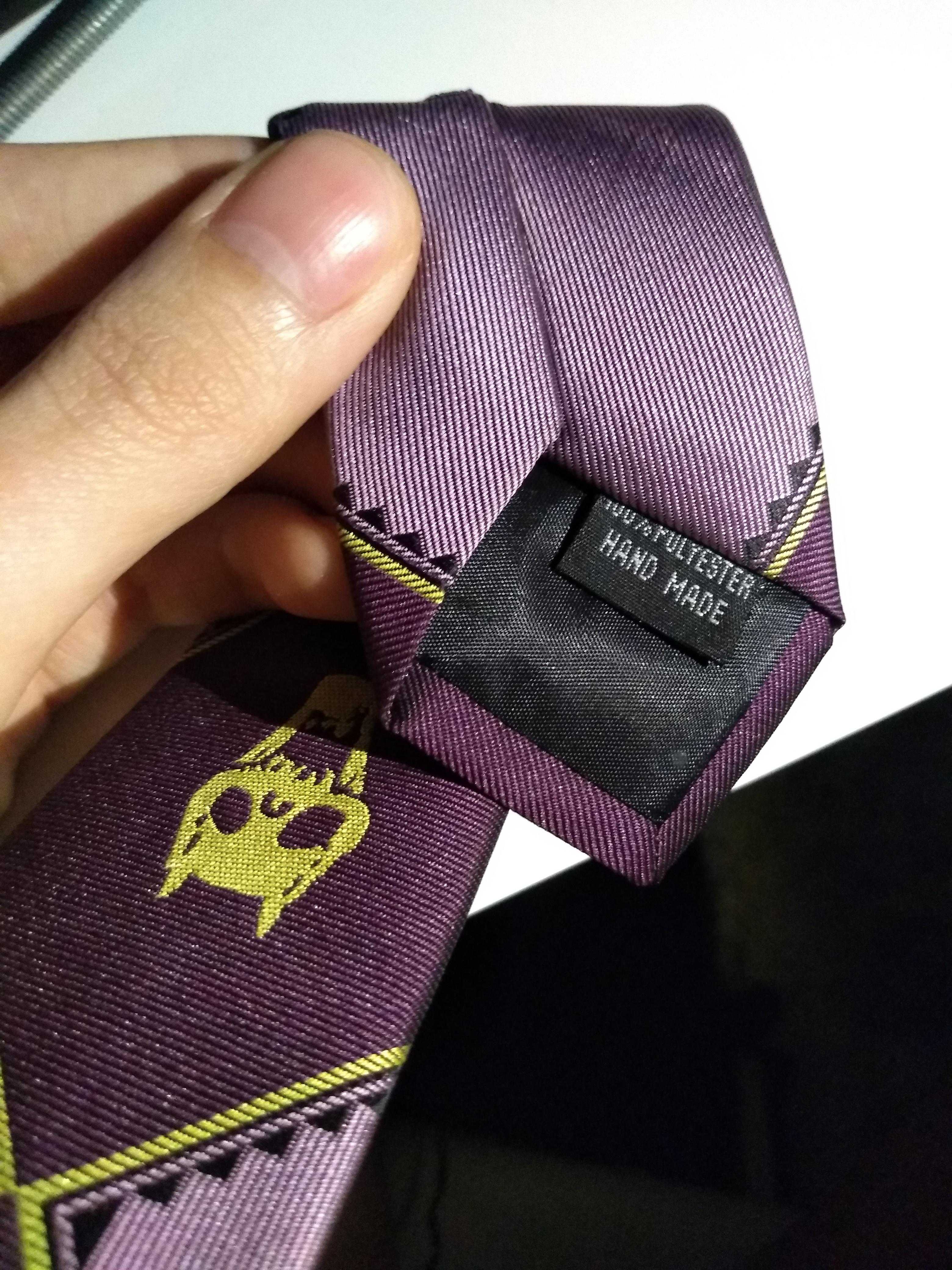 someone is holding a purple tie with a yellow design on it