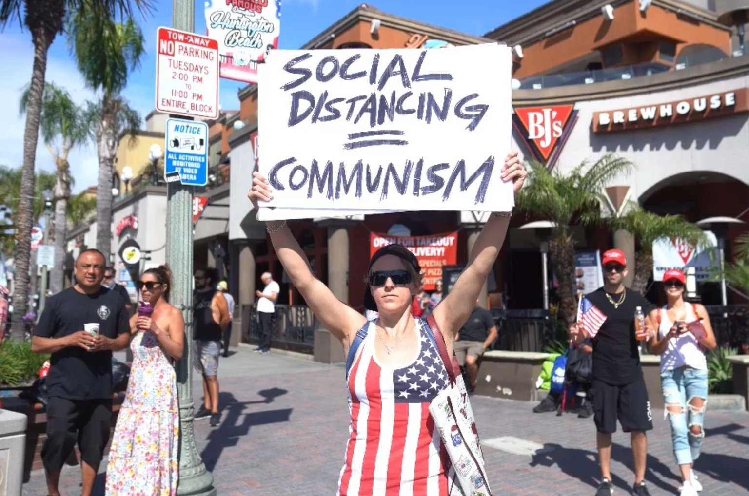 woman holding a sign that says social distancing communism