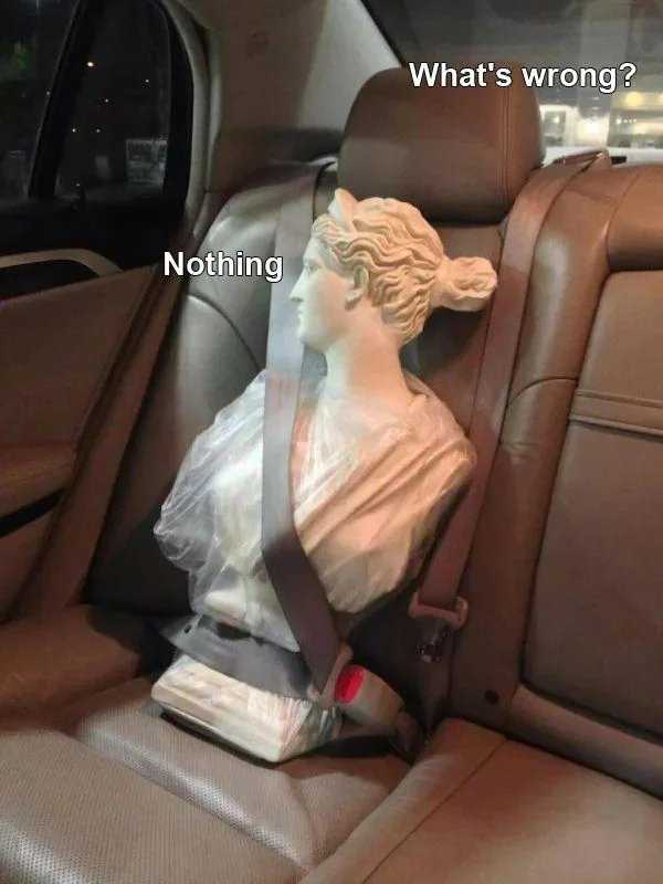 statue of a woman sitting in a car seat with a seat belt