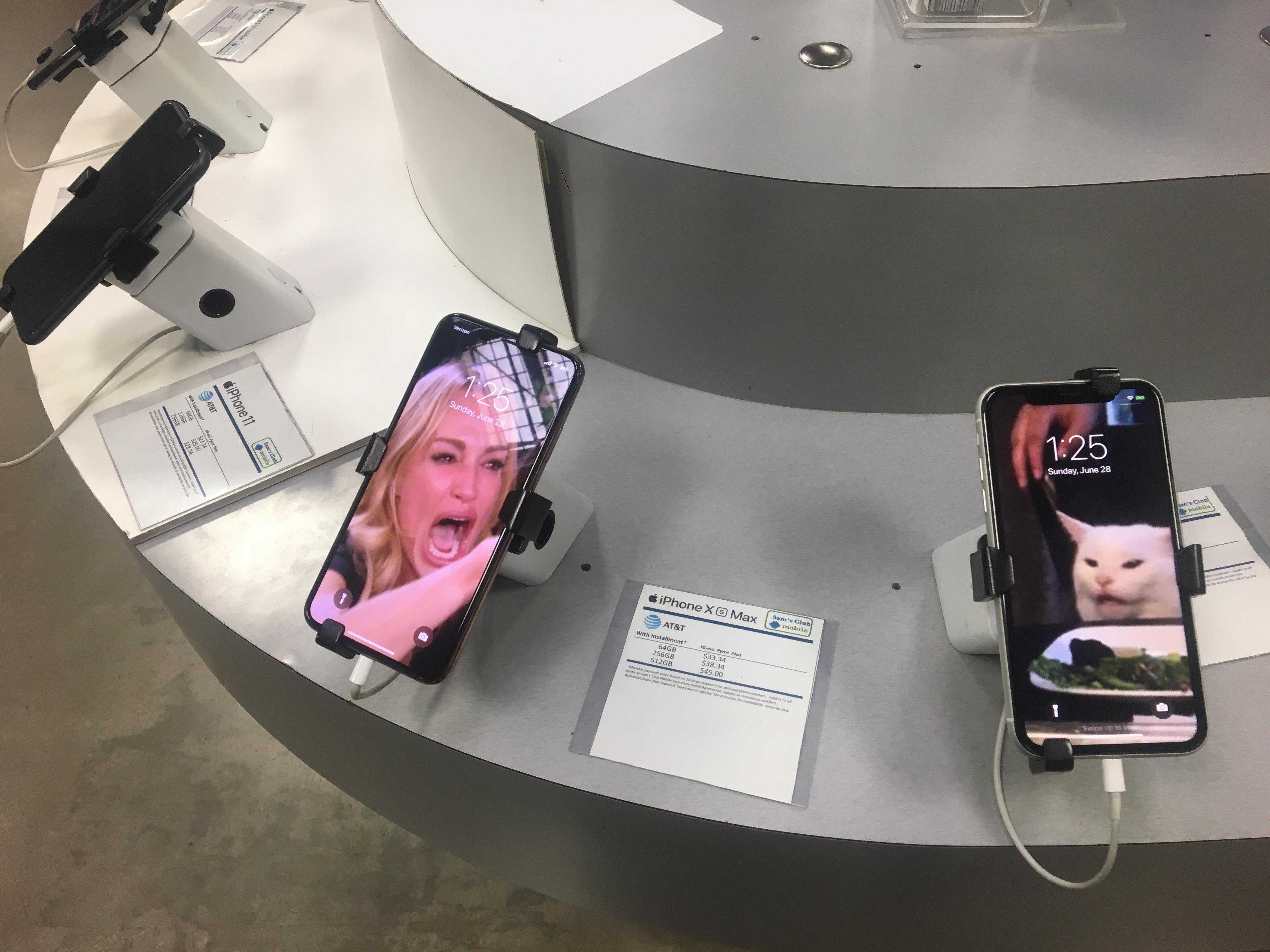 there are two phones on display on a table with a woman on the screen