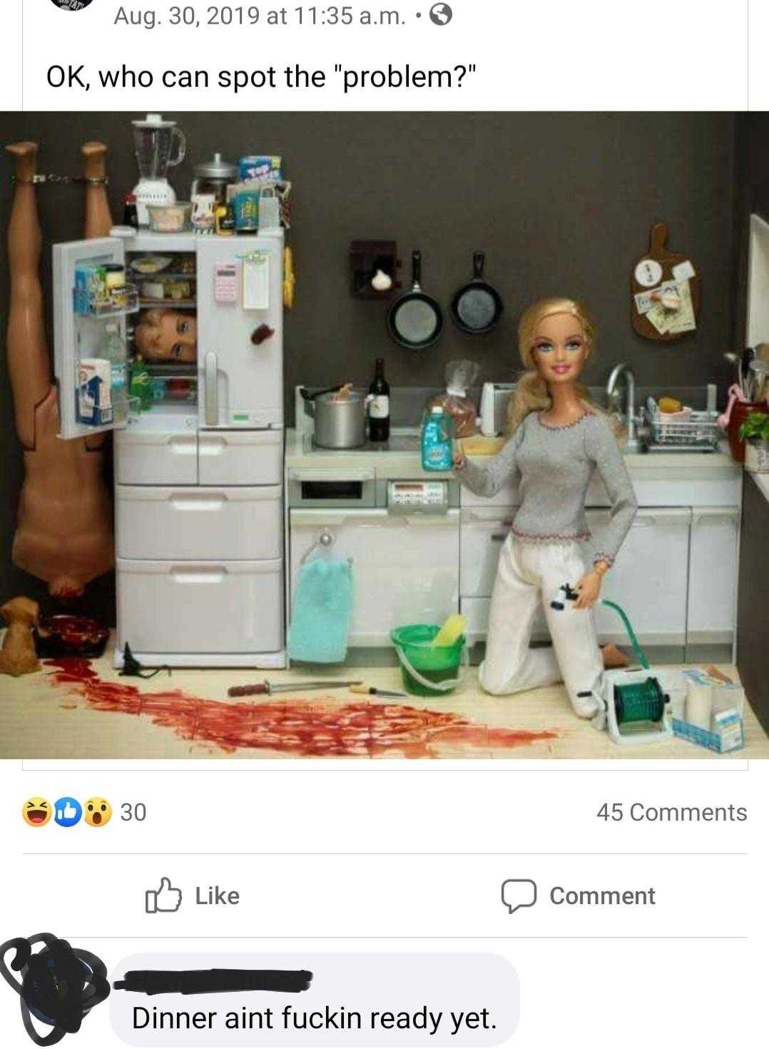 a close up of a doll in a kitchen with a refrigerator