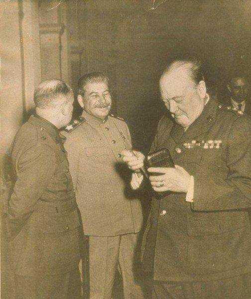 photograph of a man in uniform standing next to two men