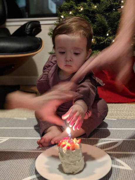 there is a small child sitting on the floor with a lit candle