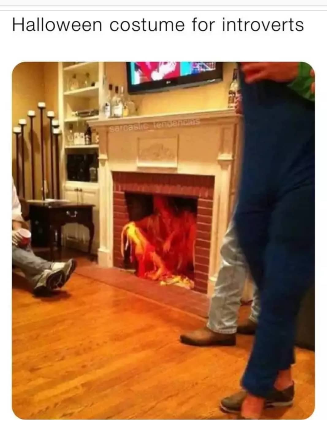 man sitting on the floor in front of a fireplace with a fire in it